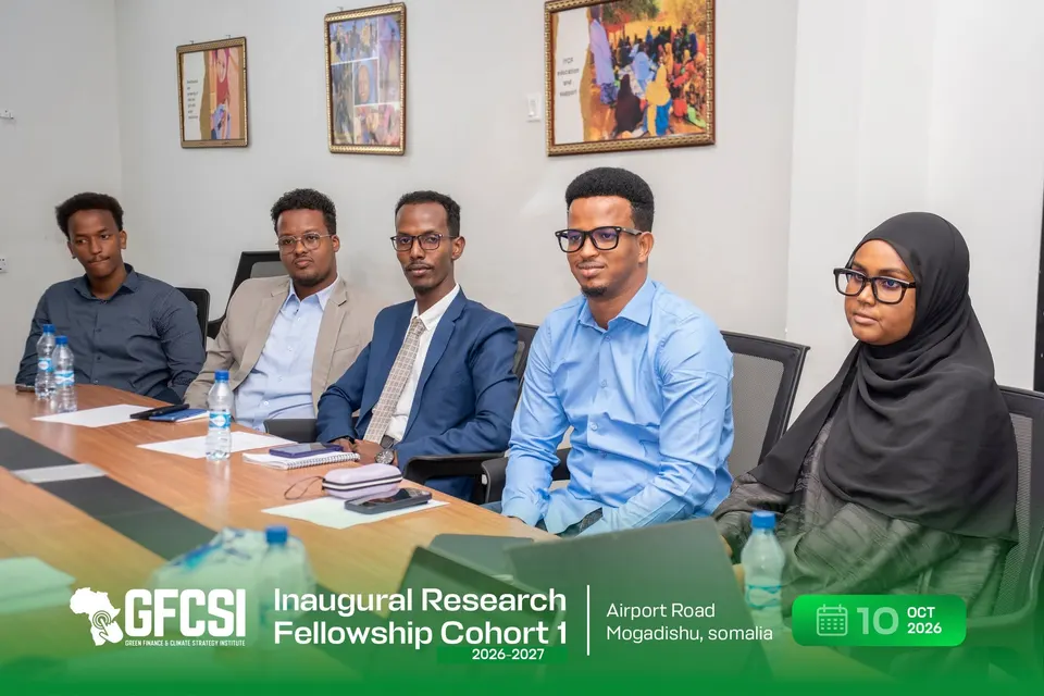 Five participants seated in a row at the conference table, listening during the induction.